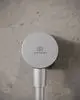 Wandanschlussbogen in Silber mit dem Logo von Ideal Standard, montiert auf einer grauen, strukturierten Wand.